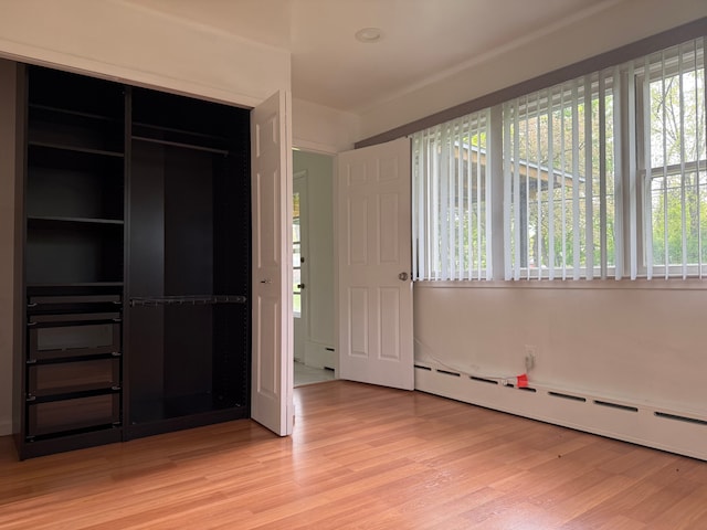5781 Wright Dr, Troy, MI 48098 - unfurnished bedroom featuring light wood-style flooring, multiple windows, baseboard heating, and a closet
