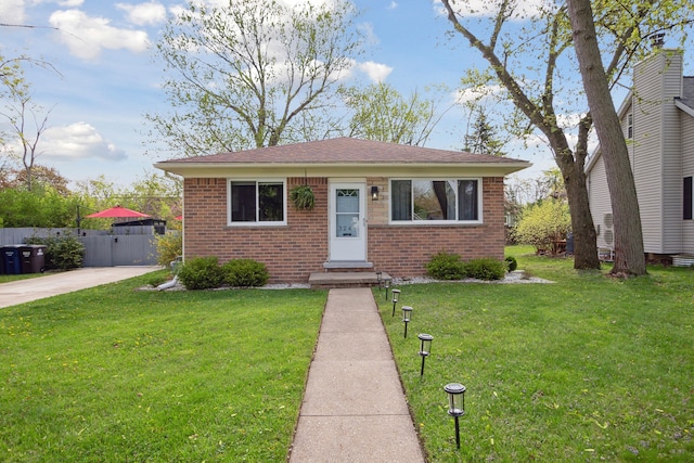 bungalow featuring fence, a shingled roof, brick siding, and a front yard