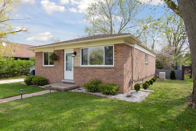 view of front of house featuring brick siding, fence, and a front yard