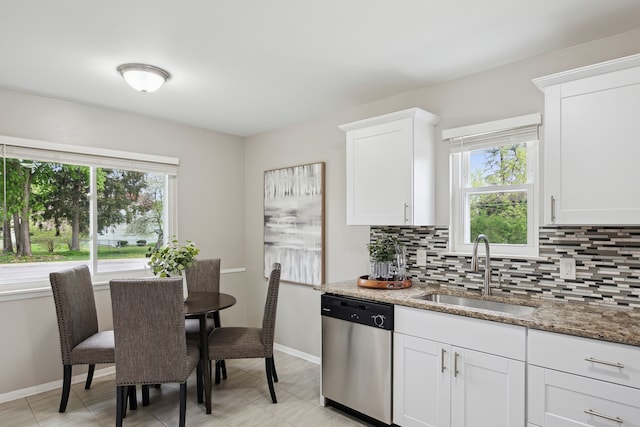 kitchen featuring a sink, dishwasher, backsplash, light stone countertops, and baseboards