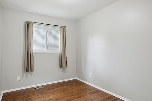 empty room featuring baseboards, visible vents, and dark wood finished floors