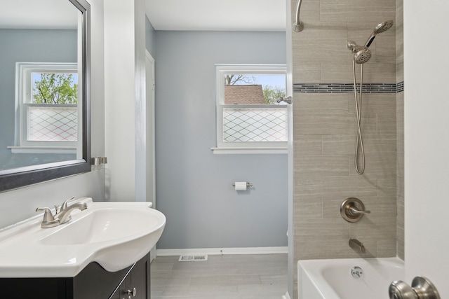 full bathroom with vanity, baseboards, a healthy amount of sunlight, and visible vents