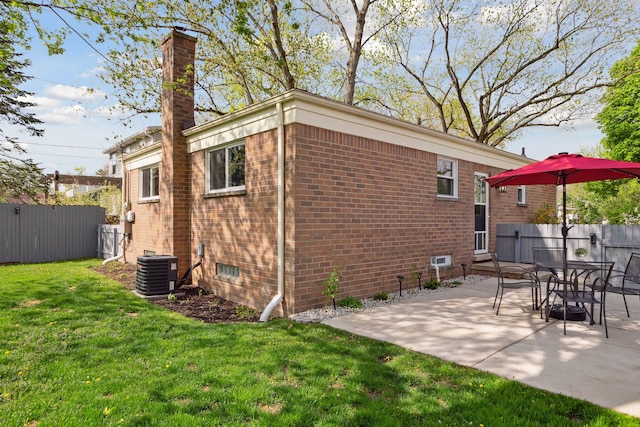 exterior space with fence, brick siding, central AC, a yard, and a chimney