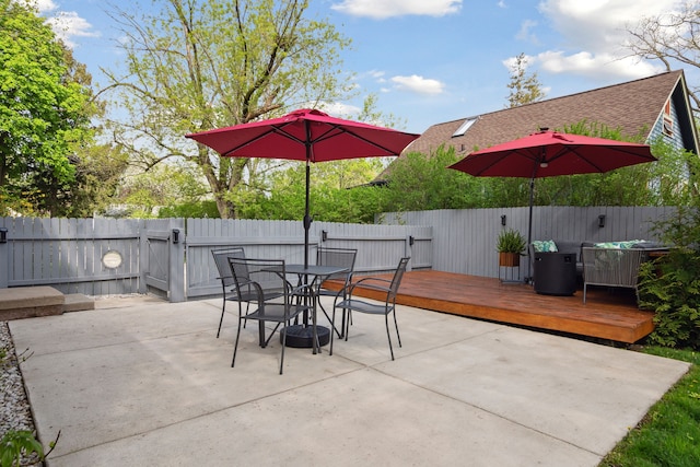 view of patio / terrace featuring a fenced backyard, a deck, a gate, and outdoor dining space
