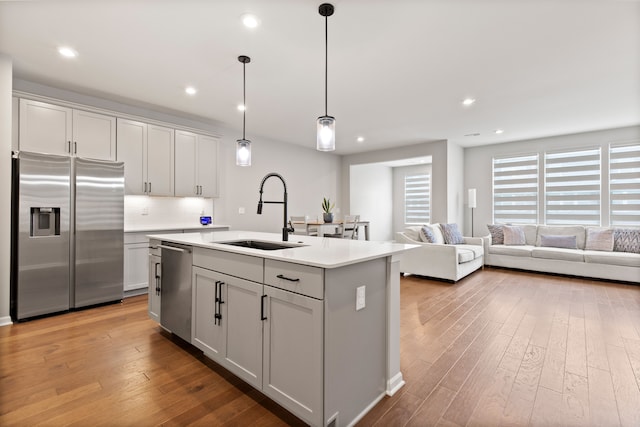 4867 Glenora Dr, Lake Orion, MI 48359 - kitchen featuring stainless steel appliances, a sink, a kitchen island with sink, wood-type flooring, and light countertops