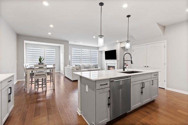 4867 Glenora Dr, Lake Orion, MI 48359 - kitchen featuring stainless steel dishwasher, a sink, a glass covered fireplace, light countertops, and dark wood-style flooring