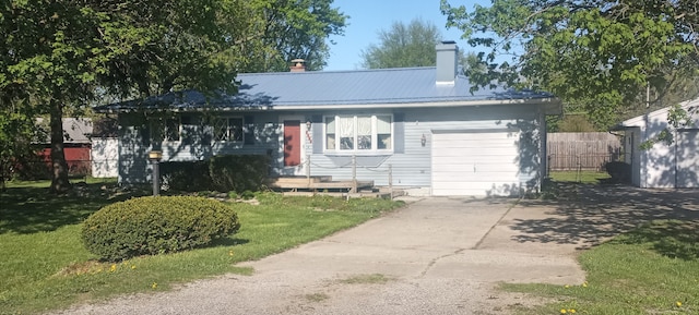 view of front of house featuring a chimney, a garage, driveway, and metal roof