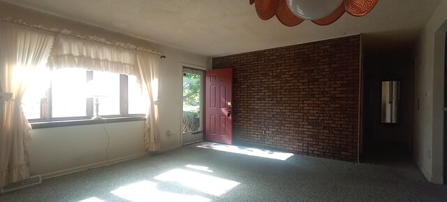carpeted spare room featuring brick wall