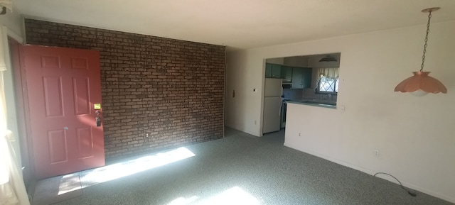 spare room featuring brick wall and light carpet