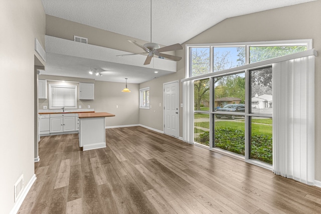 4938 Lincoln Blvd, Dearborn Heights, MI 48125 - kitchen with butcher block countertops, white cabinets, a textured ceiling, a sink, and wood finished floors