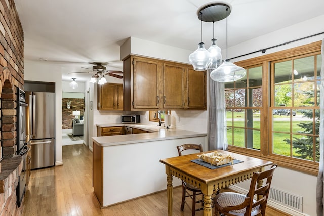 kitchen with stainless steel appliances, visible vents, a sink, a peninsula, and light countertops