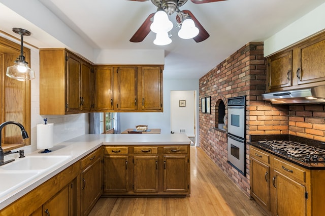 kitchen with ceiling fan, a peninsula, stainless steel double oven, and light wood-style flooring