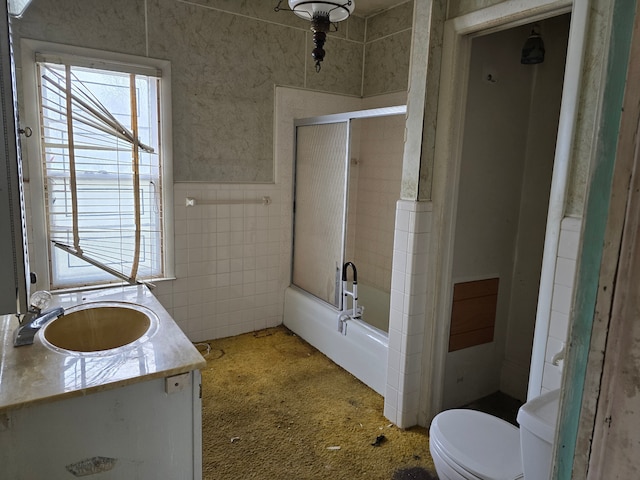 1315 Mitchell St, Jackson, MI 49203 - bathroom featuring vanity, tile walls, combined bath / shower with glass door, and toilet