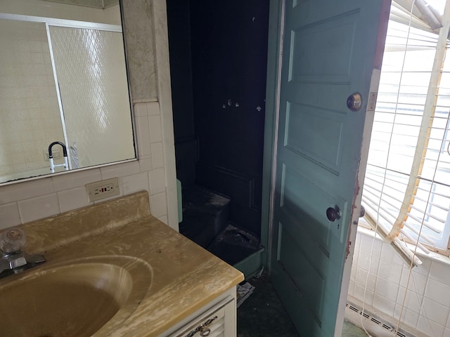 1315 Mitchell St, Jackson, MI 49203 - full bath with vanity, a shower with shower door, backsplash, and baseboard heating