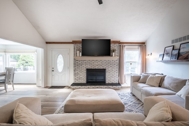 living room with a brick fireplace, visible vents, a healthy amount of sunlight, and wood finished floors