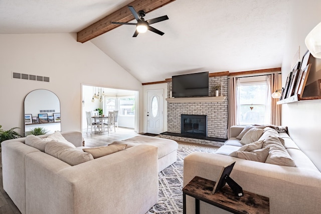 living room with plenty of natural light, beamed ceiling, wood finished floors, and visible vents