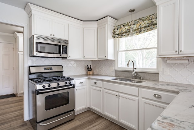 kitchen with a sink, appliances with stainless steel finishes, decorative backsplash, and white cabinetry