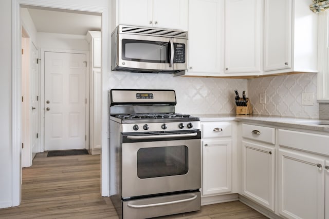 kitchen with light wood-style floors, white cabinetry, appliances with stainless steel finishes, and tasteful backsplash