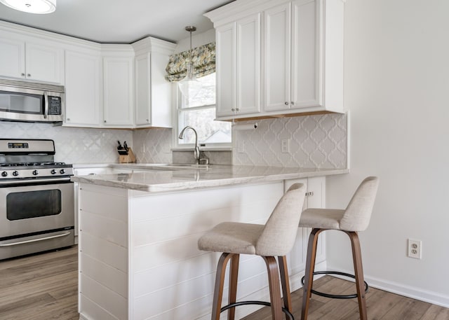 kitchen with a sink, a breakfast bar, stainless steel appliances, and white cabinetry