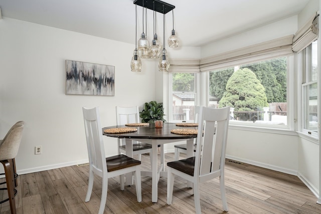 dining room featuring baseboards, visible vents, and wood finished floors
