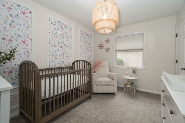 bedroom with baseboards, a crib, and carpet