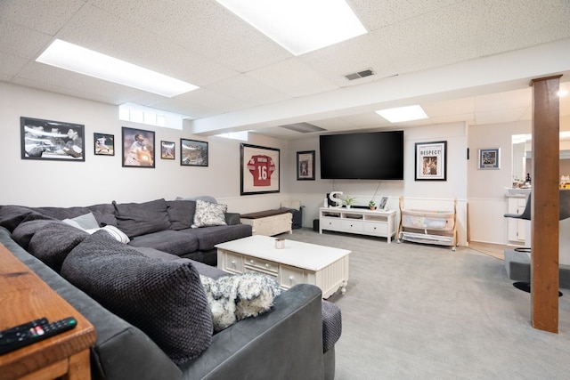 living room featuring light colored carpet, a drop ceiling, and visible vents