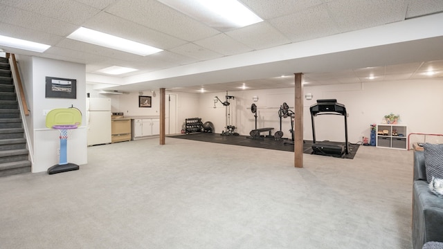 exercise area featuring light colored carpet and a paneled ceiling