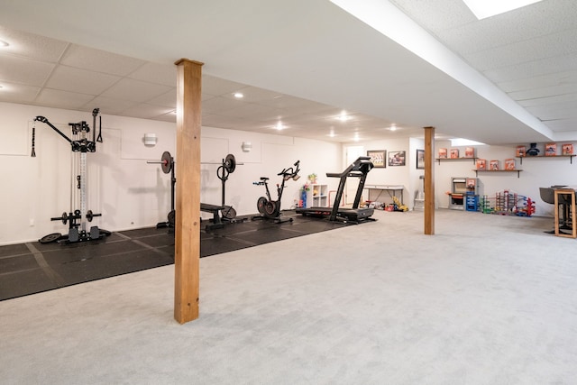 exercise room with a paneled ceiling and carpet