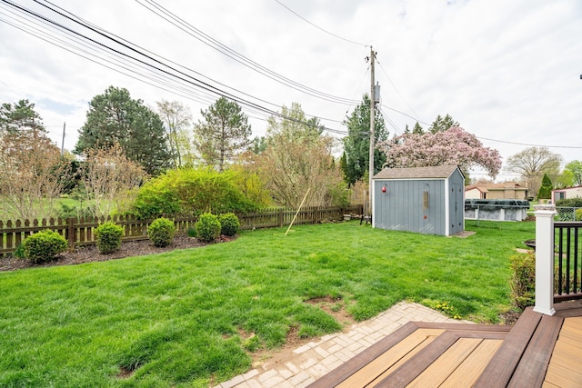 view of yard featuring a fenced backyard, a storage unit, and an outbuilding