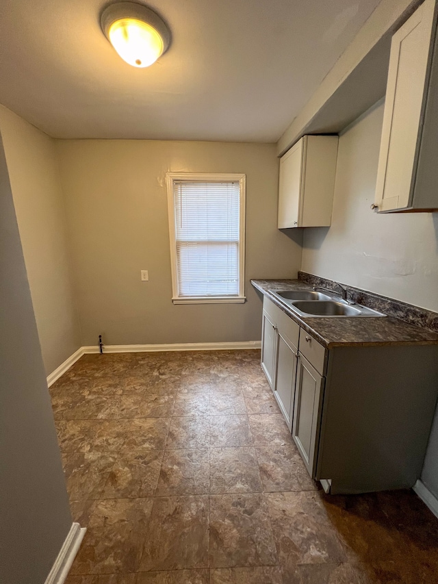 19190 Hoover St, Detroit, MI 48205 - kitchen with a sink, dark countertops, white cabinets, and baseboards