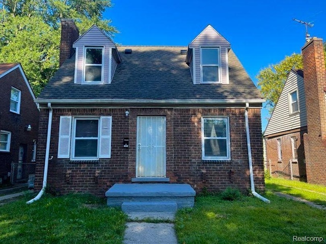 16895 Cruse St, Detroit, MI 48235 - view of front facade featuring a chimney, brick siding, a front yard, and roof with shingles