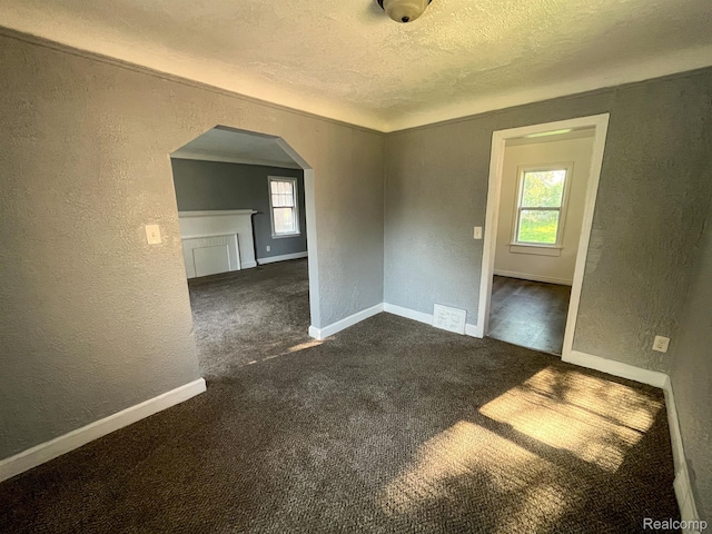 16895 Cruse St, Detroit, MI 48235 - unfurnished room with a textured wall, a textured ceiling, arched walkways, dark colored carpet, and baseboards
