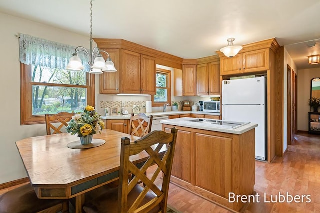 kitchen with a center island, light countertops, light wood finished floors, a chandelier, and white appliances