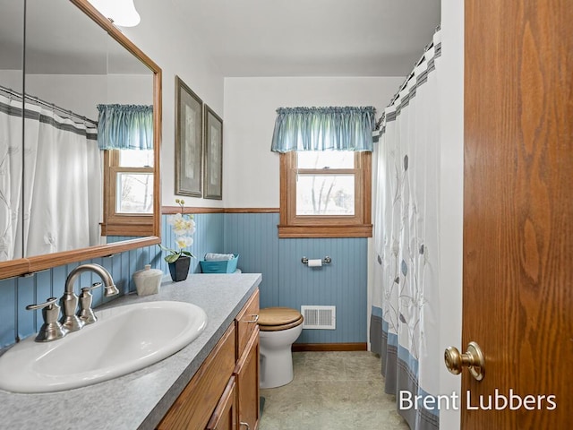full bathroom with visible vents, wainscoting, vanity, baseboards, and toilet