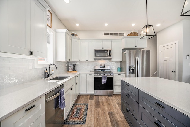 22873 Riverside Dr, Mendon, MI 49072 - kitchen with appliances with stainless steel finishes, a sink, white cabinets, dark wood-style flooring, and recessed lighting
