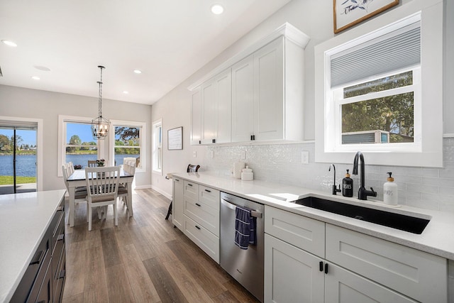 22873 Riverside Dr, Mendon, MI 49072 - kitchen with stainless steel dishwasher, a sink, dark wood-style flooring, light countertops, and backsplash