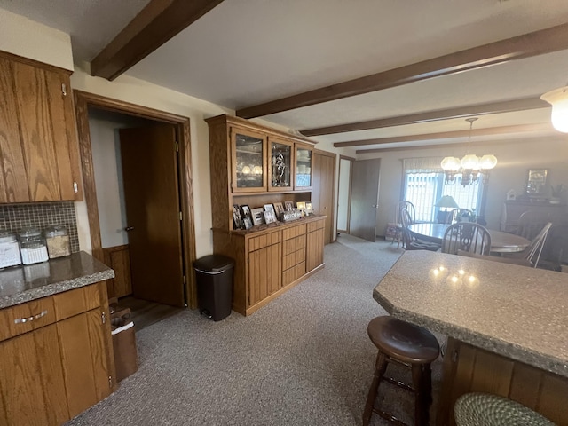 kitchen with light colored carpet, brown cabinetry, and beam ceiling