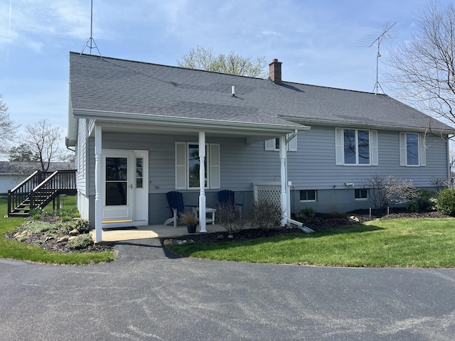 view of front of home featuring roof with shingles, a chimney, a porch, and stairway