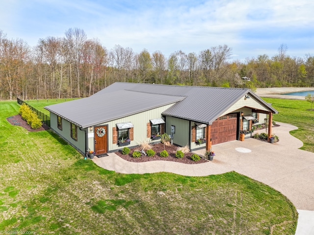 view of front of home featuring metal roof, concrete driveway, an attached garage, and a front yard