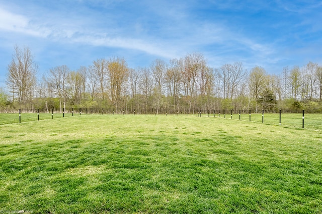 view of yard with fence and a rural view