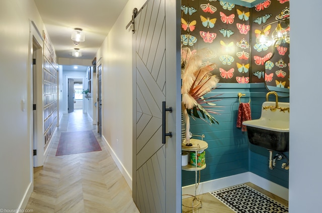 hall with baseboards, a barn door, and a sink