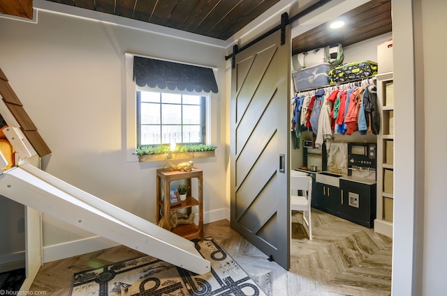interior space with baseboards, recessed lighting, a barn door, and wood ceiling