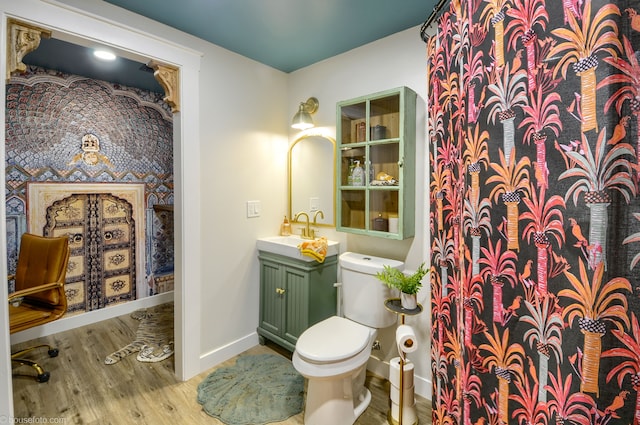 bathroom featuring toilet, baseboards, vanity, and wood finished floors