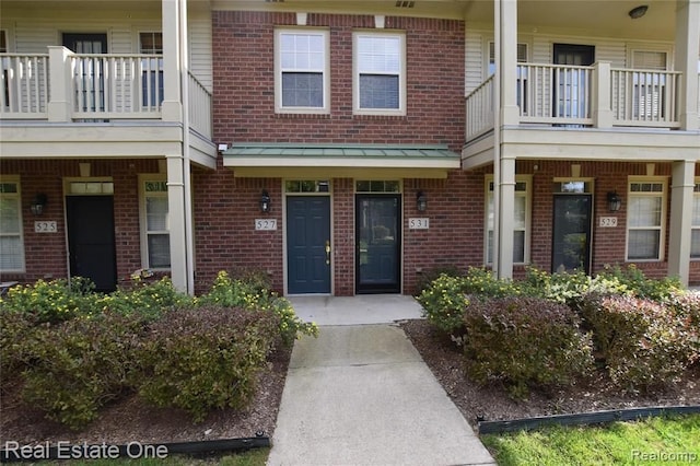 entrance to property featuring brick siding and a balcony