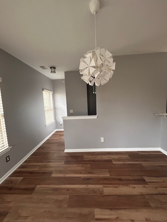 unfurnished dining area with an inviting chandelier, baseboards, dark wood-style floors, and visible vents