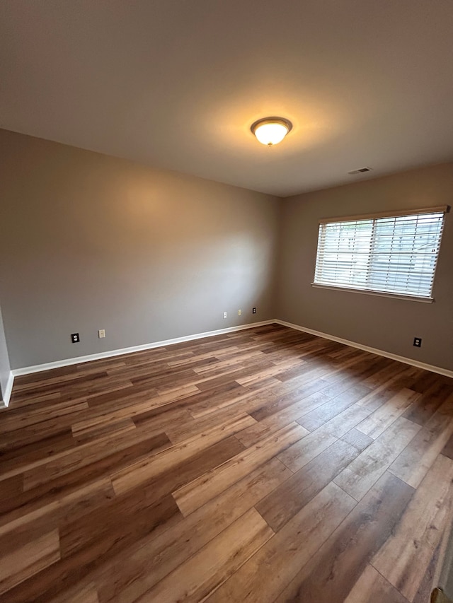 unfurnished room with visible vents, baseboards, and dark wood-style floors