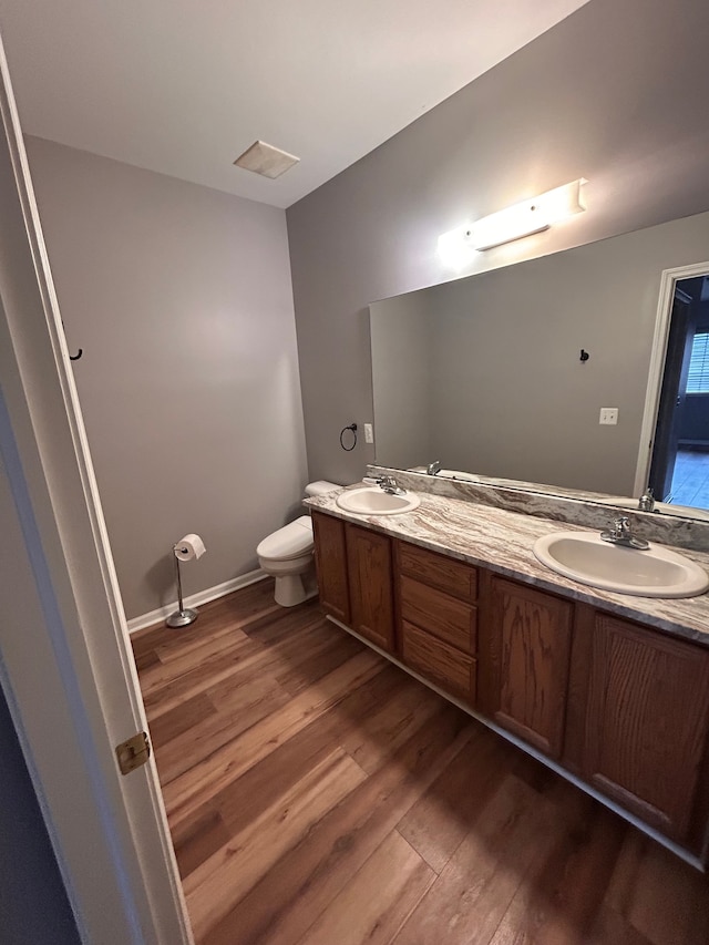 full bathroom with double vanity, wood finished floors, and a sink