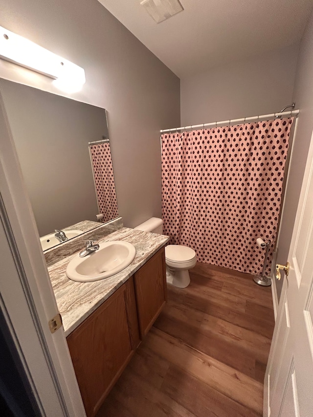 bathroom featuring vanity, toilet, wood finished floors, and visible vents