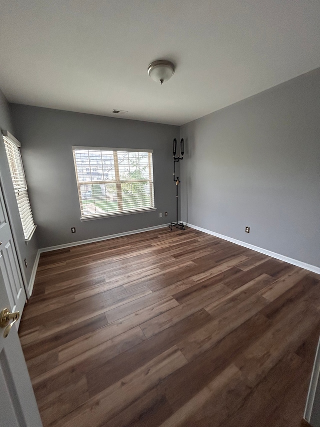 spare room with baseboards and dark wood-style floors