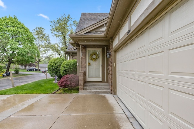 26901 Ann Arbor Trl, Dearborn Heights, MI 48127 - view of exterior entry featuring a shingled roof, a garage, driveway, and brick siding